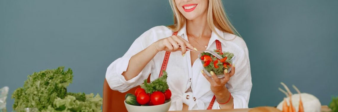 Blonde woman enjoying a fresh salad surrounded by vegetables, promoting healthy eating.