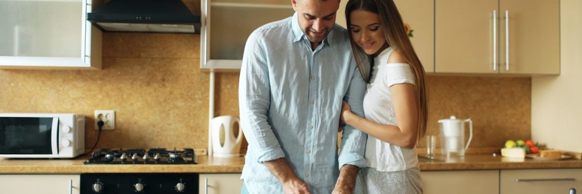 Happy young couple in the kitchen. Handsome man meet his girlfriend early morning at home